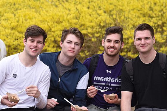 四名立博体育官网的男生在外面微笑着吃冰淇淋