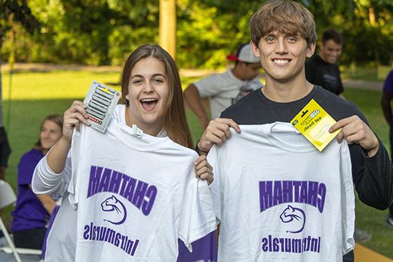 图为两名立博体育官网的学生举着他们的校内运动t恤，面带微笑
